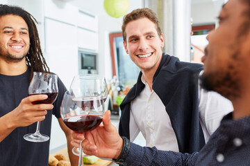 Wall Mural - Freunde beim Anstoßen mit Glas Rotwein in der Küche auf Feier