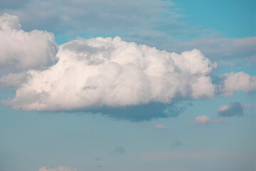 Big white fluffy clouds in blue sky. Summer background. Perspective.