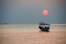 Seascape With Fishermens Boat  In Asian Ocean At Sunset With Red Sun And Soft Tones