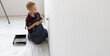 © Andrii Lysenko - a boy dressed in overalls stands in the room holding a roller with paint and paints the wall. Home renovation concept.