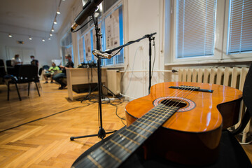 Acoustic guitar sitting on chair in front of the microphones before performance