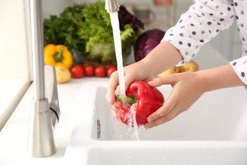 Wall Mural - Woman washing fresh red bell pepper in kitchen sink, closeup