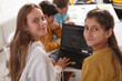 © mad_production - Happy teenage girls smiling to the camera while working on a school project together, using laptop