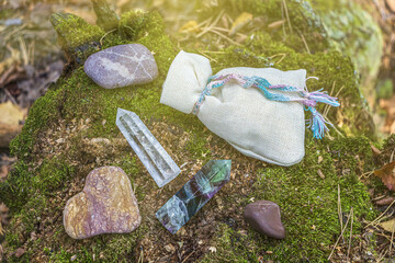 Wall Mural - Magic still life with fluorite, quartz crystal, candle and bag with potion (herb). Rocks for mystic ritual, witchcraft Wiccan or spiritual healing on stump in forest. Ritual for love.