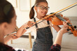 © New Africa - Young woman teaching little girl to play violin indoors