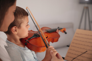 Canvas Print - Young woman teaching little boy to play violin indoors, closeup