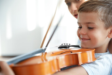 Canvas Print - Young woman teaching little boy to play violin indoors, closeup