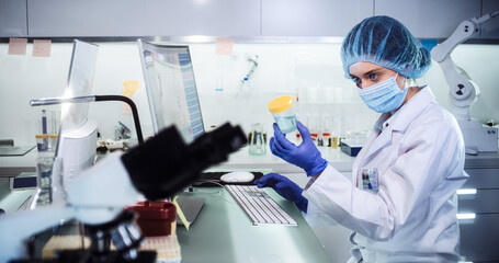 Wall Mural - female doctor working in futuristic laboratory. wearing protective workwear for biohazardous sample 