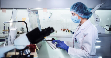 Wall Mural - female doctor working in futuristic laboratory. wearing protective workwear for biohazardous sample 
