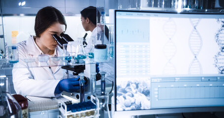 Wall Mural - female doctors testing samples in futuristic laboratory. using microscopes and computer with data