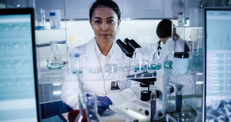 Wall Mural - multi ethnic science team working with microscope and computer. female doctors in futuristic laborat