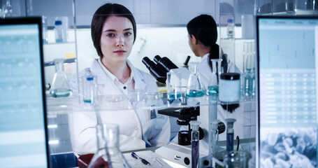 Wall Mural - multi ethnic science team working with microscope and computer. female doctors in futuristic laborat