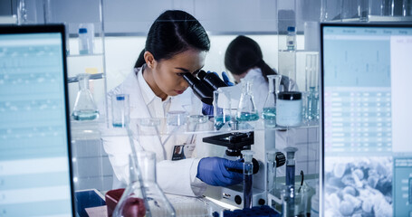 Wall Mural - multi ethnic science team working with microscope and computer. female doctors in futuristic laborat
