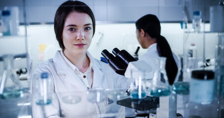 Wall Mural - multi ethnic science team working with microscope and computer. female doctors in futuristic laborat