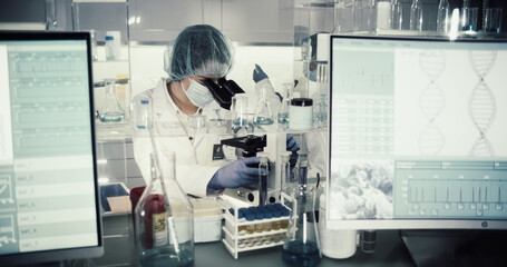Wall Mural - asian female doctor working with biohazardous samples. using microscope in futuristic laboratory