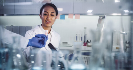 Wall Mural - asian female doctor working in futuristic laboratory. using microscope and computer for blood sample