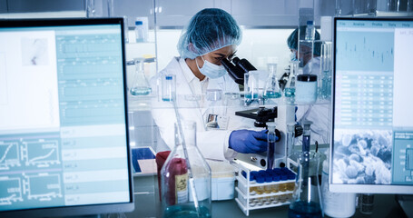 Wall Mural - female science team working on biohazardous samples. using microscope and computer with data