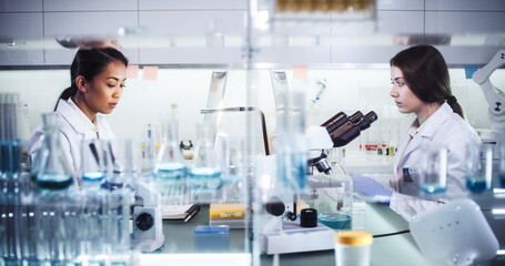 Wall Mural - female doctors testing samples in futuristic laboratory. using microscopes and computer with data