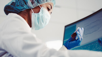Wall Mural - asian female doctor working with biohazardous samples. using microscope in futuristic laboratory
