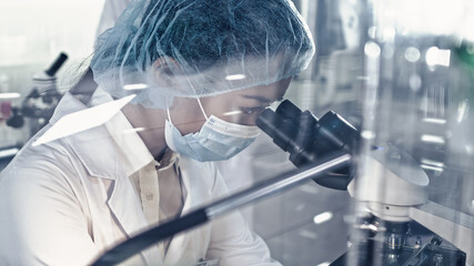 Wall Mural - asian female doctor working with biohazardous samples. using microscope in futuristic laboratory
