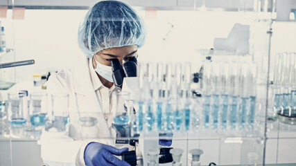 Wall Mural - asian female doctor working with biohazardous samples. using microscope in futuristic laboratory