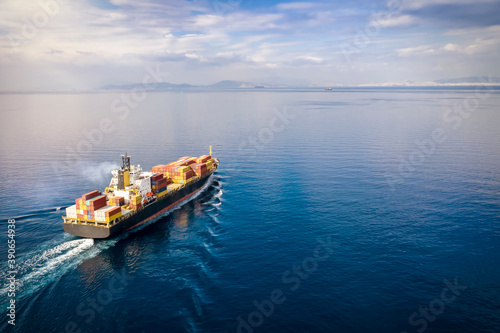 Fotomural Aerial view of a loaded cargo container ship traveling over calm ocean towards t