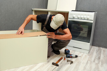 Wall Mural - worker assembles furniture in the kitchen. furniture assembly service concept