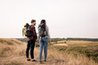 © LIGHTFIELD STUDIOS - Smiling couple of multiethnic hikers holding hands while looking at landscape on blurred background