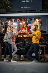 Wall Mural -  group of customers toasting and eating in front of modified truck for mobile fast food service