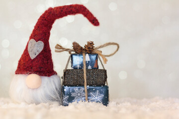 Christmas gnome and christmas presents on snowy and shiny background with copy space