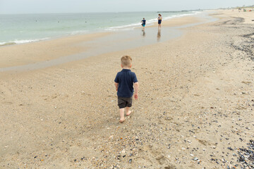 Boy Walks Toward His Family Near Water on New Jersey Seashore