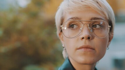 Wall Mural - Portrait of young caucasian blond short haired woman with eyeglasses in the park. High quality 4k footage