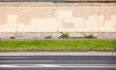 Urban road roadside with green grass and concrete wall