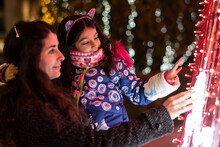 Mother With Little Daughter Looking City Christmas Lights. Focus Is On Child, Ambient Light Image.