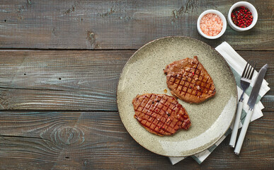 Wall Mural - Two grilled ribeye steaks, spices and tomato-cucumber salad with sour cream on a wooden table.