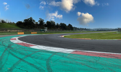 Asphalt turn track on motorsport circuit with large green trap area and brake skid marks