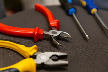 Wall Mural - Laying a wire pair of pliers and screwdrivers locksmith work tool close-up on a dark background