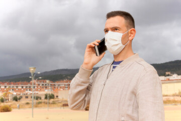 Spanish man wearing reusable facial mask at the street. Concept covid-19 pandemic.