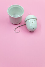 Vertical Shot Of A White Tea Strainer With An Infuser Isolated On A Pink Background