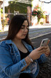 © Leon Colon Ortega - Young woman looking at her cellphone in the parcel in an afternoon