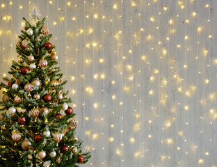 decorated christmas tree over grey wall with lights