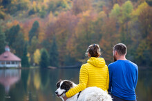 Couple In Love With Dog Relaxing At The Lake.