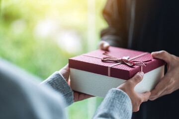 Closeup image of a man giving a woman a gift box