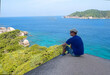 © milly777 - A young man sits on a stone in the Similan Islands and gazes at the blue transparent clear Andaman sea.
