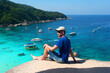 © milly777 - A young man sits on a stone in the Similan Islands and gazes at the blue transparent clear Andaman sea.