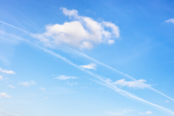 Wall Mural - contrail and fluffy cumuli clouds in blue sky on autumn day