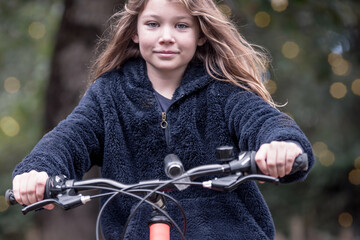 Wall Mural - cute little girl riding a bicycle in an autumn park