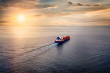 Aerial View Of A Container Cargo Ship Sailing Over Calm Sea Into The Sunset