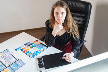 Poster - UX designer. Application design. Woman designer uses graphic electronic tablet. Mobile app templates are drawn on paper. Web designer is working on a smartphone app. Girl works in a web design studio