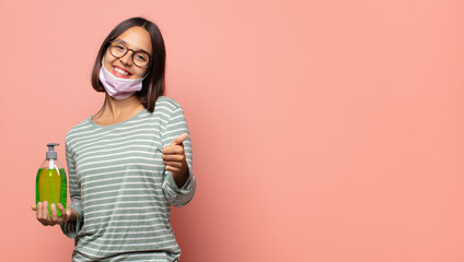 young woman feeling proud, carefree, confident and happy, smiling positively with thumbs up